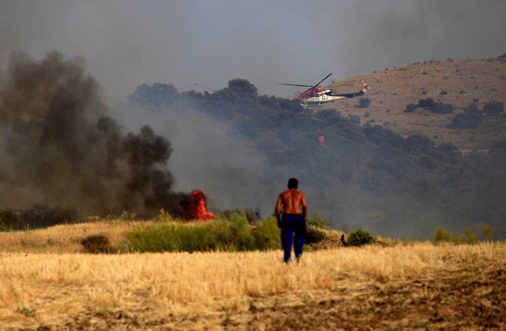 Un vecino contempla los trabajos de extinción de un helicóptero.