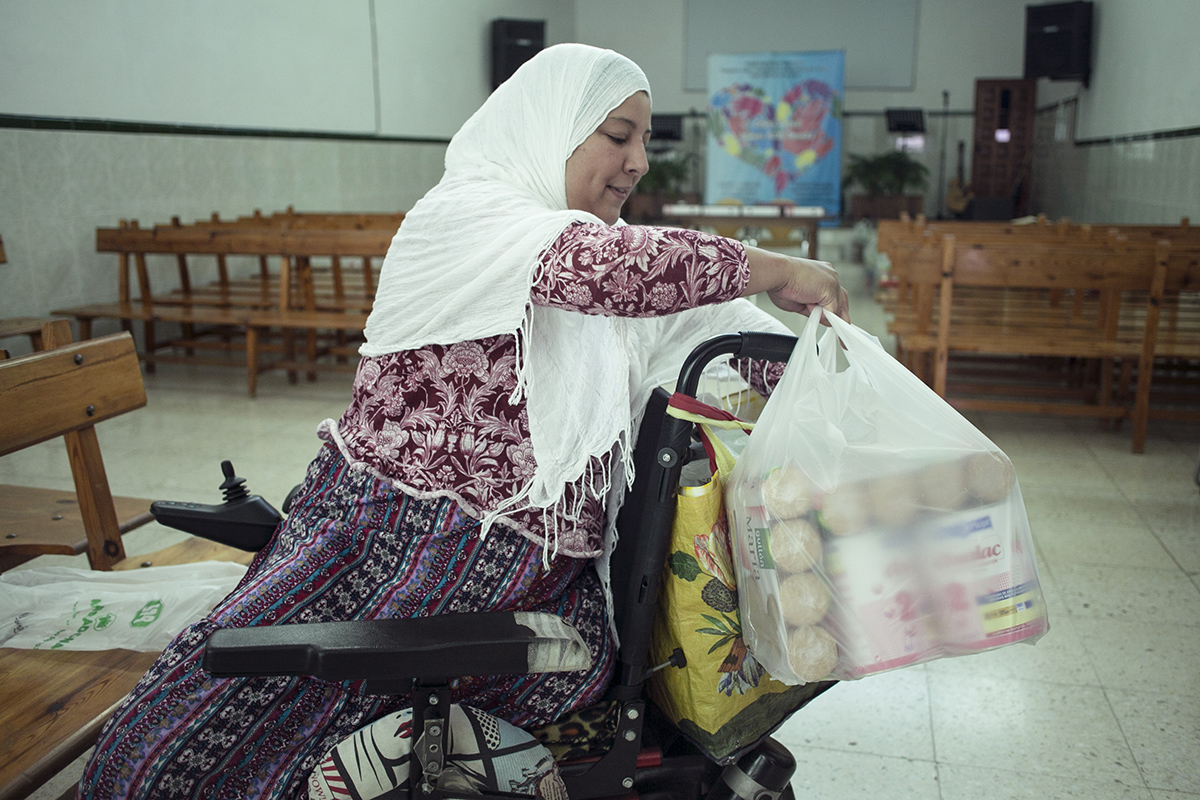 Loubna prepara los alimentos que le han entregado para transportarlos en su silla de ruedas