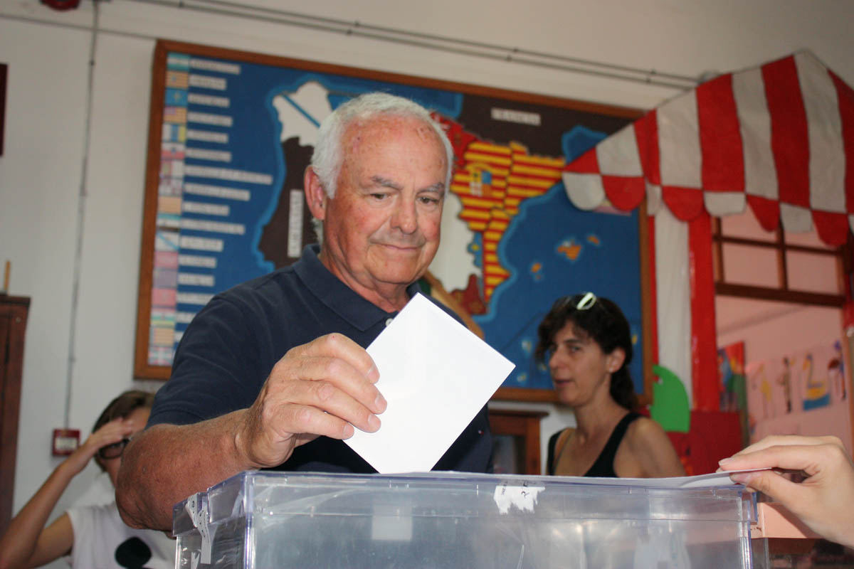 Un cuiudadano vota en el colegio Juan Carrillo con el mapa de España de fondo.