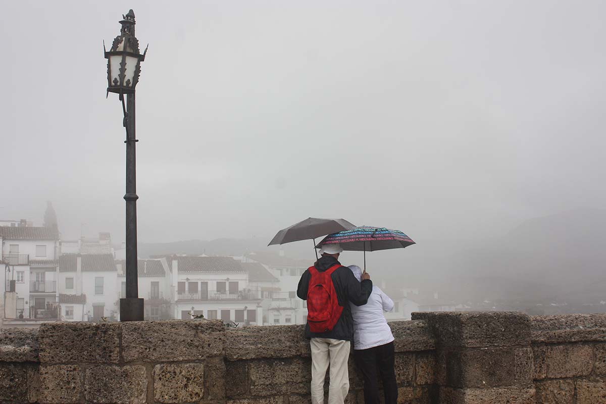 Una pareja de turistas contempla la niebla desde el Puente Nuevo.