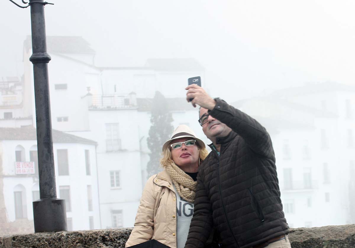 Dos turistas se fotografían en el Tajo de Ronda con ropa de abrigo.