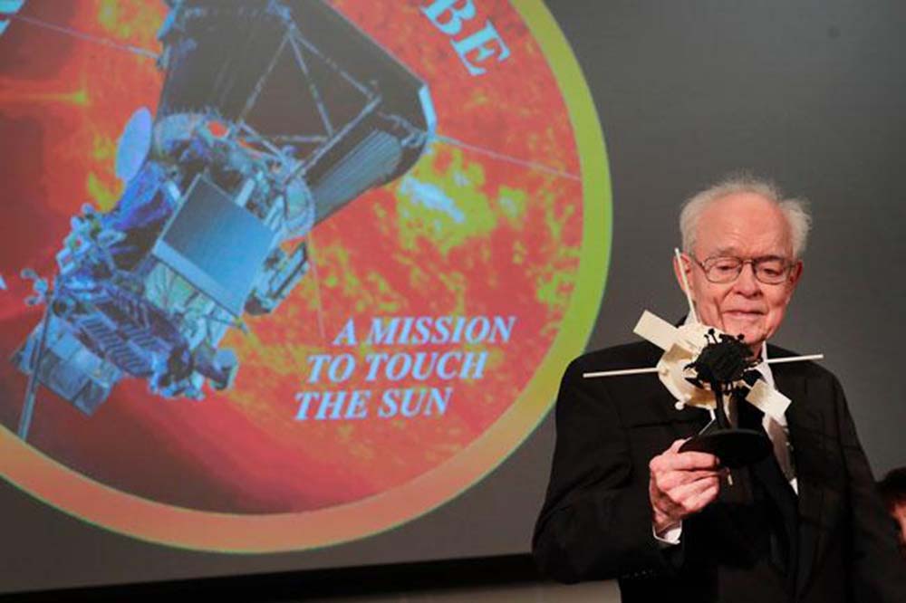 Parker, con una maqueta y el logo de la misión (NASA).
