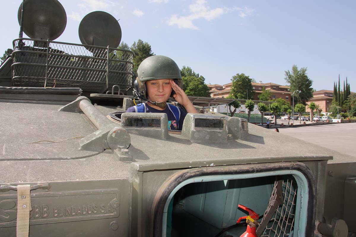 Un niño realiza el saludo militar desde el interior de uno de los vehículos acorazados.