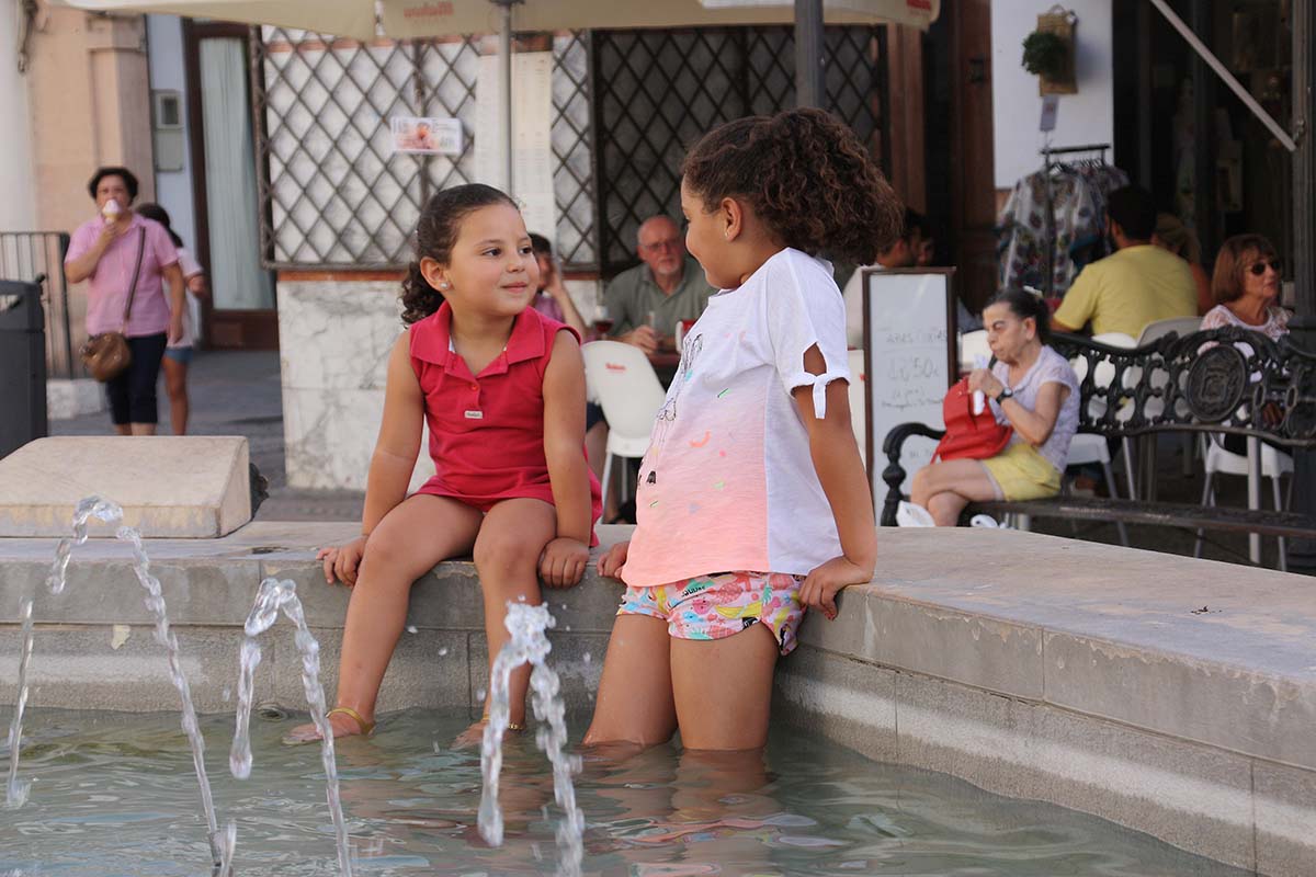 Dos pequeñas se refrescan en la fuente de la plaza del Socorro.