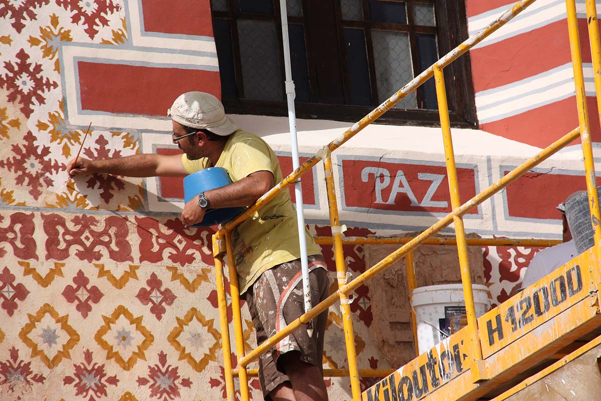 Un operario pinta con gran cuidado los decorados de la fachada del santuario de la Paz.