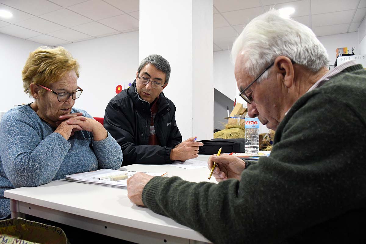 Dos personas mayores de parauta participan en una clase junto a su profesor.