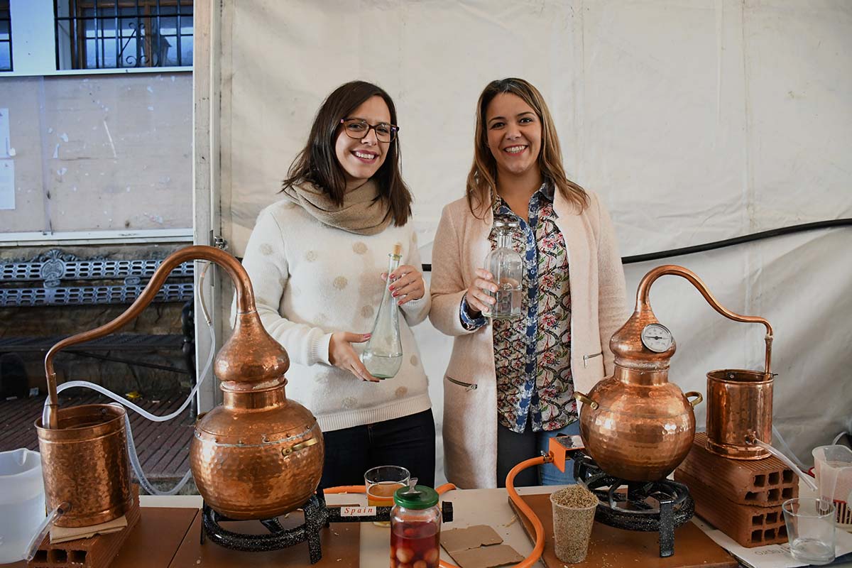 Dos jóvenes destiladoras con su aguardiente junto a los alambiques.