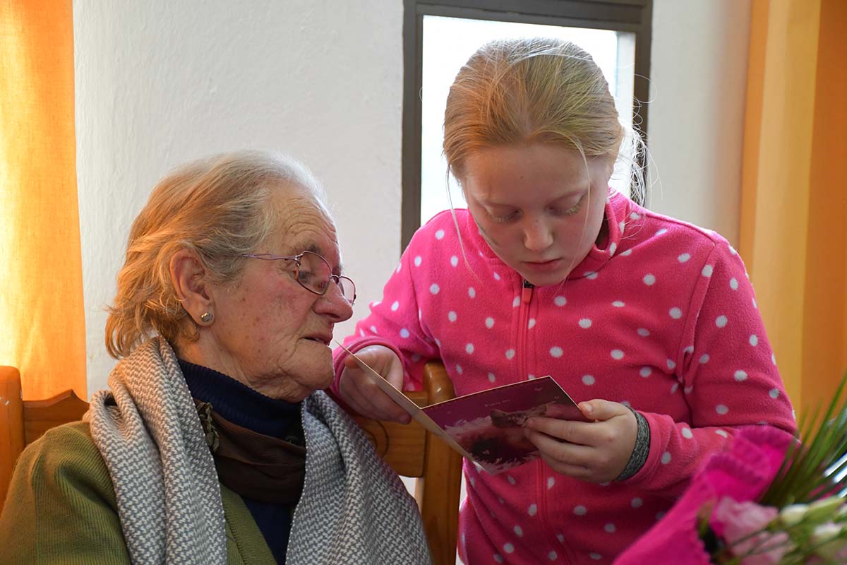 Una niña del pueblo lee a una persona mayor una carta de San Valentín.