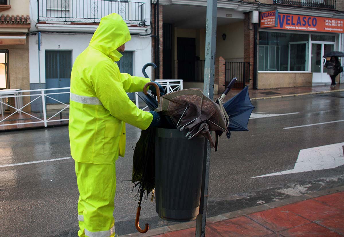Un empleado de Soliarsa retira de una papelera numerosos paraguas rotos por el viento.