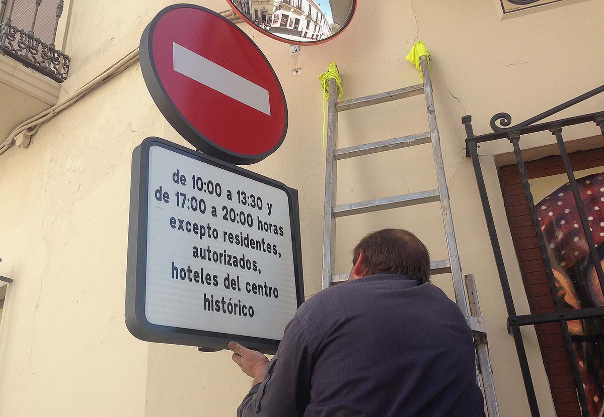 Un operario de Tráfico coloca una señal en la calle Armiñán con la nueva leyenda.