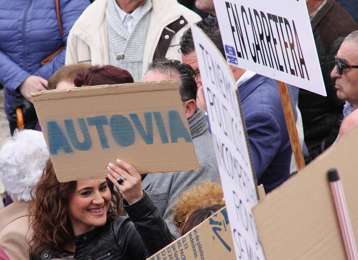 Una manifestante portando un cartel por la autovía en la manifestación del 30 de abril.