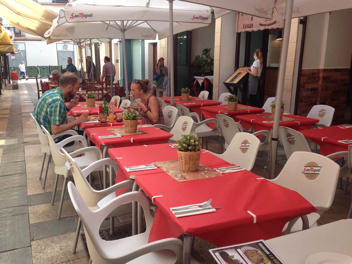 Dos turistas almuerzan en una desierta calle Nueva durante un día de la Feria.