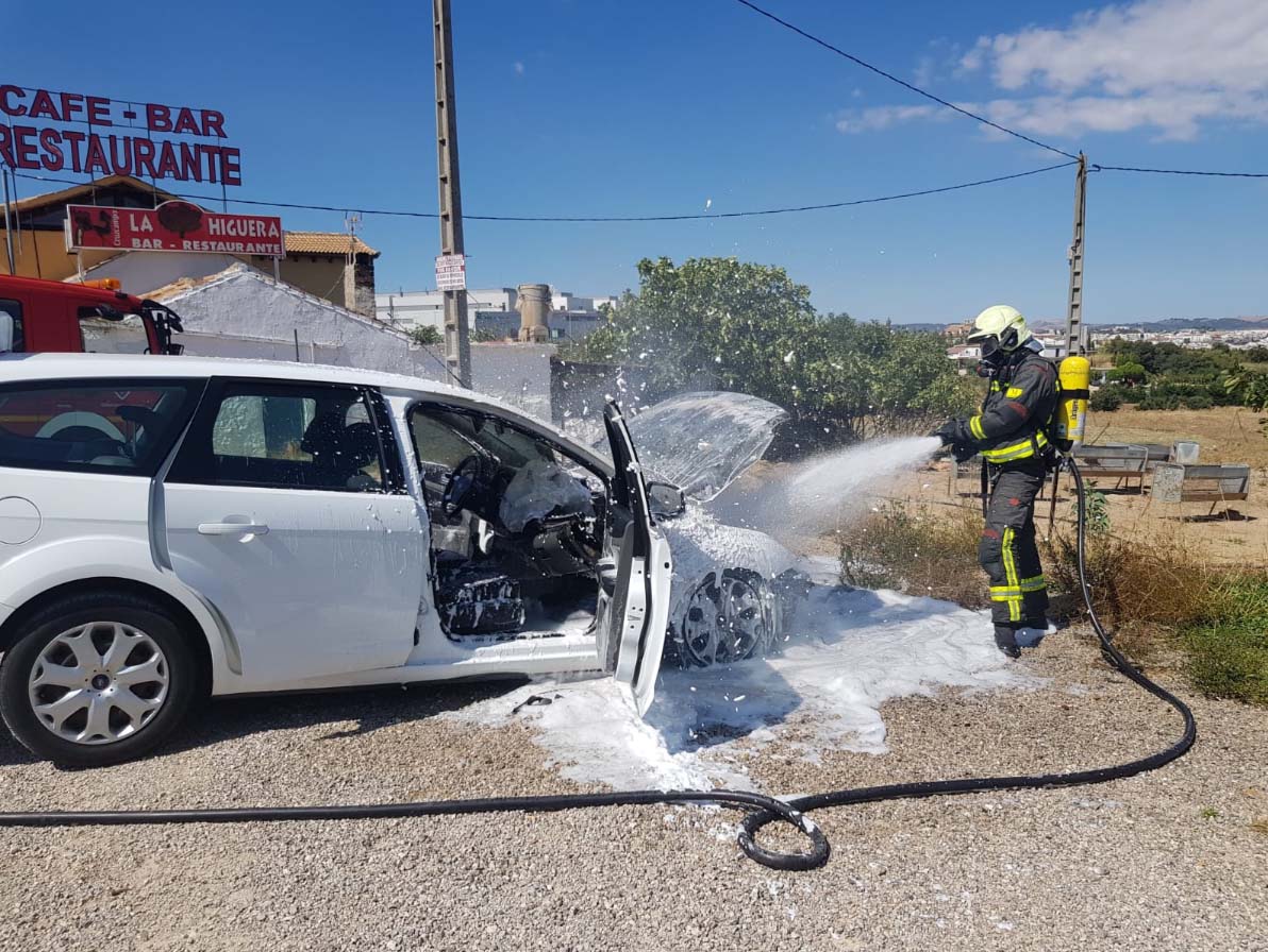 Momento en el que los bomberos apagan el incendio declarado en un turismo.