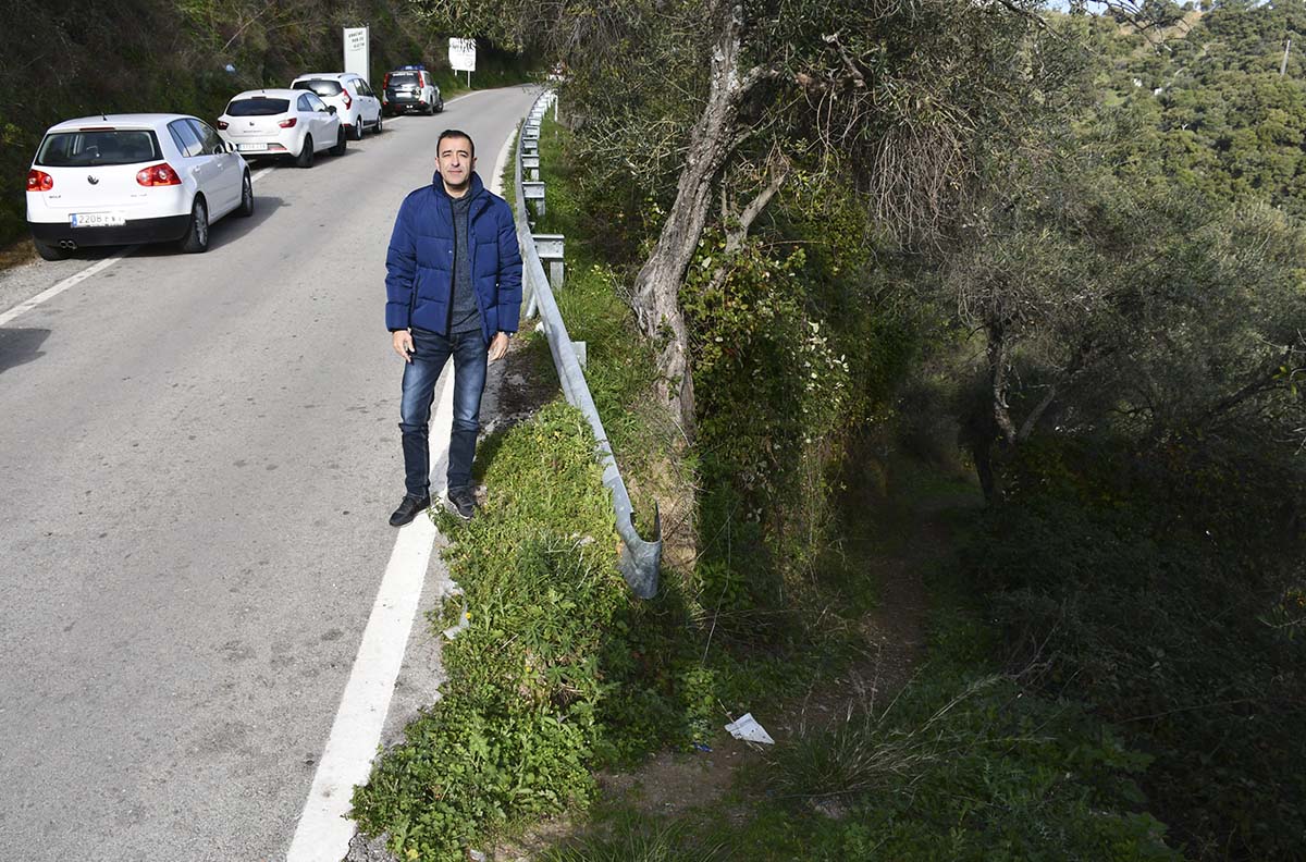El alcalde muestra los problemas de estacionamiento que tiene el pueblo, con coches aparcados en la carretera de entrada.