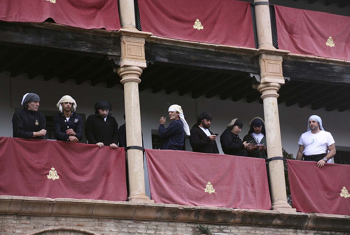Costaleros de la Vera Cruz siguen la evolución de las nubes con sus móviles momentos previos a la suspensión de la procesión.
