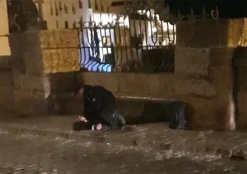 Momento en el que el policía local reduce al joven tras bajarlo del muro del Puente Nuevo.