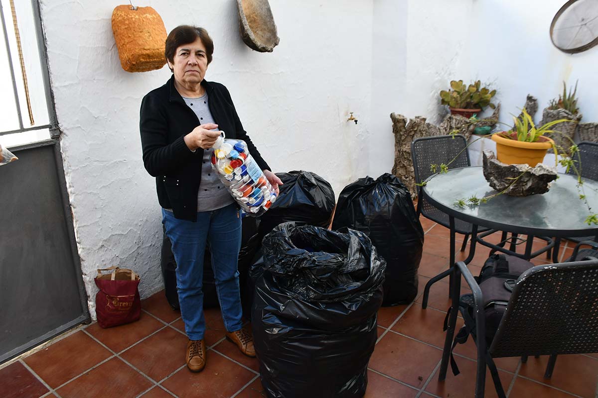 María Becerra, en el patio de su casa, con las bolsas en las que recogen los tapones.