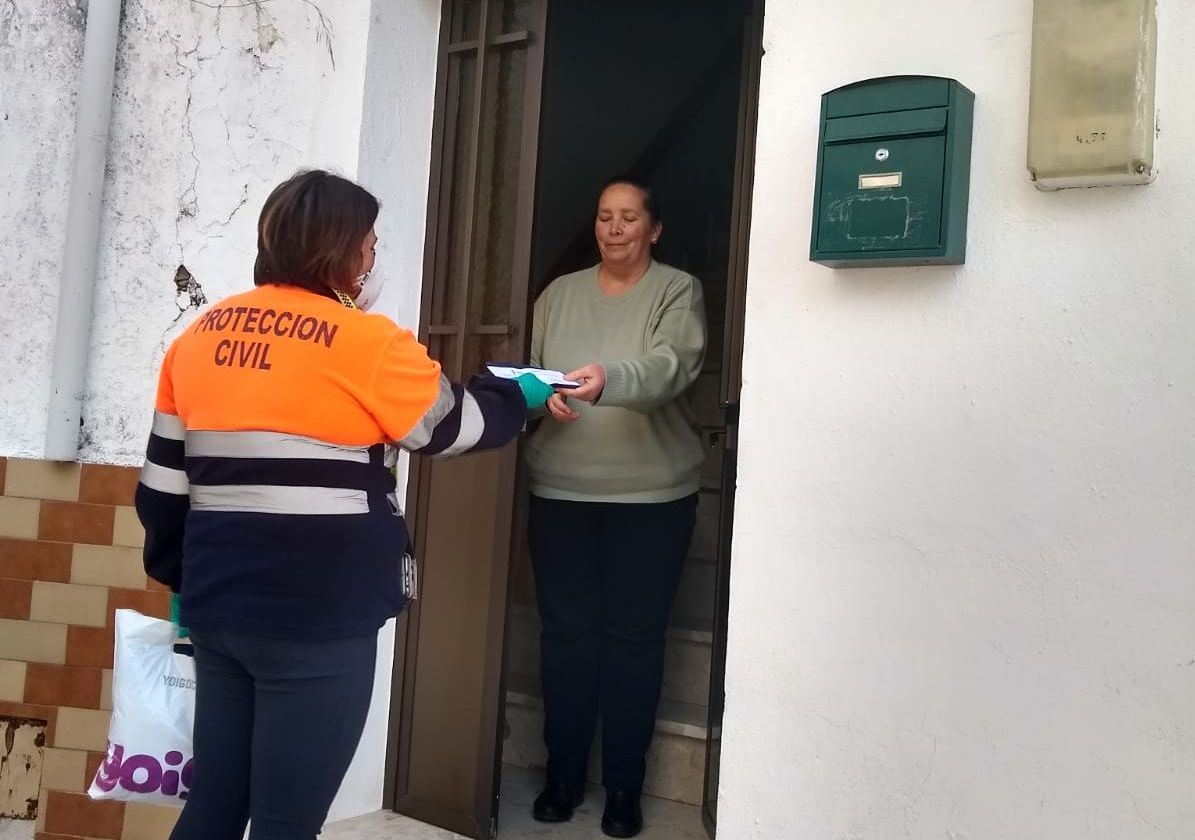 Una voluntaria de Protección Civil reparte mascarillas a los vecinos.