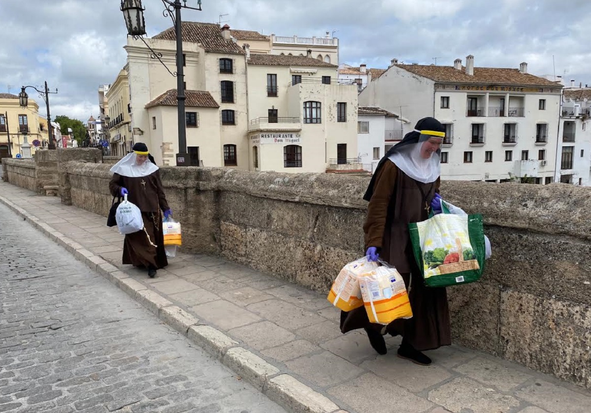 Las hermanas de la Cruz en el Puente Nuevo cargadas de bolsas para los necesitados.