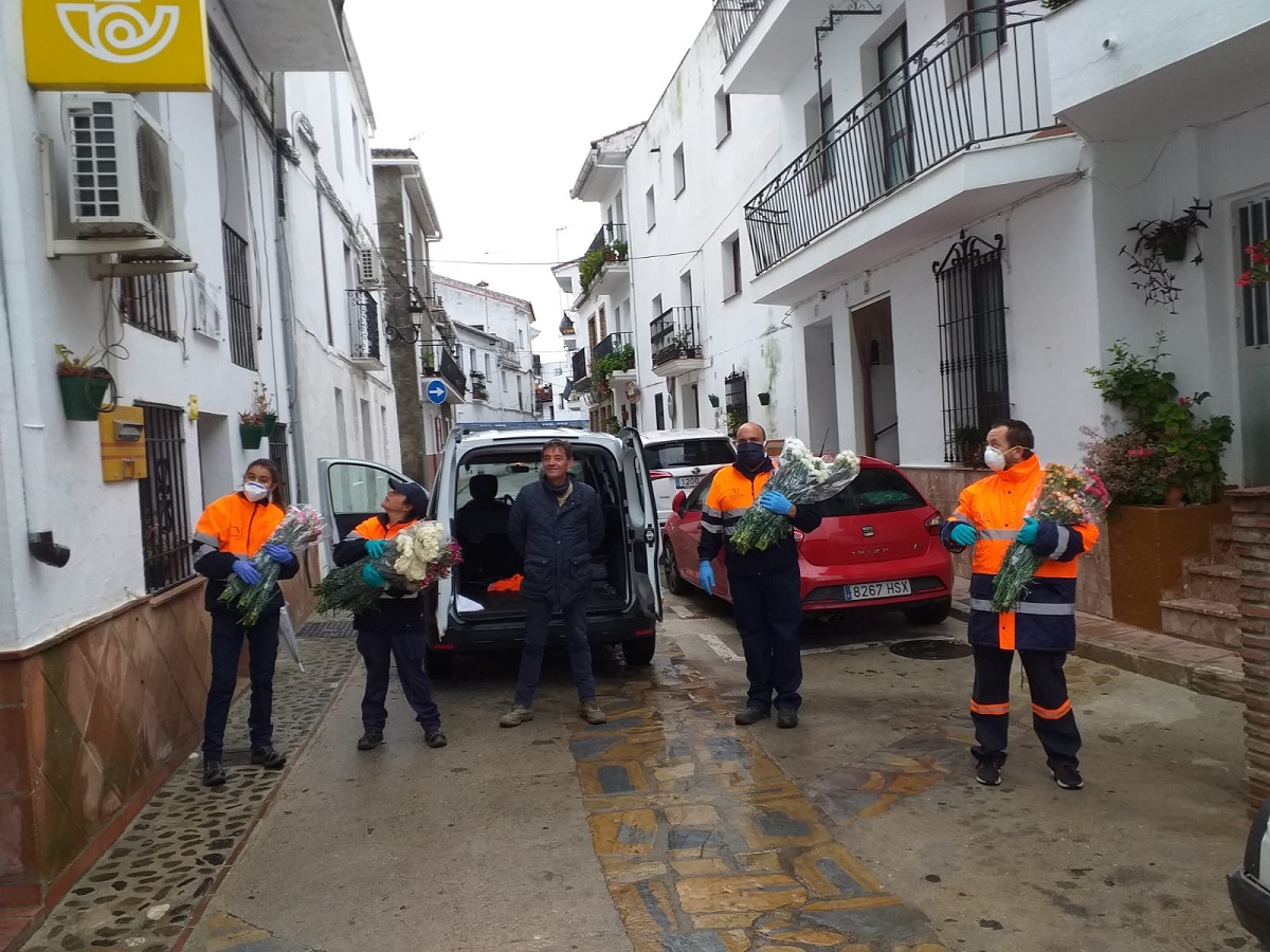 El alcalde y voluntarios de Protección Civil repartiendo las flores.
