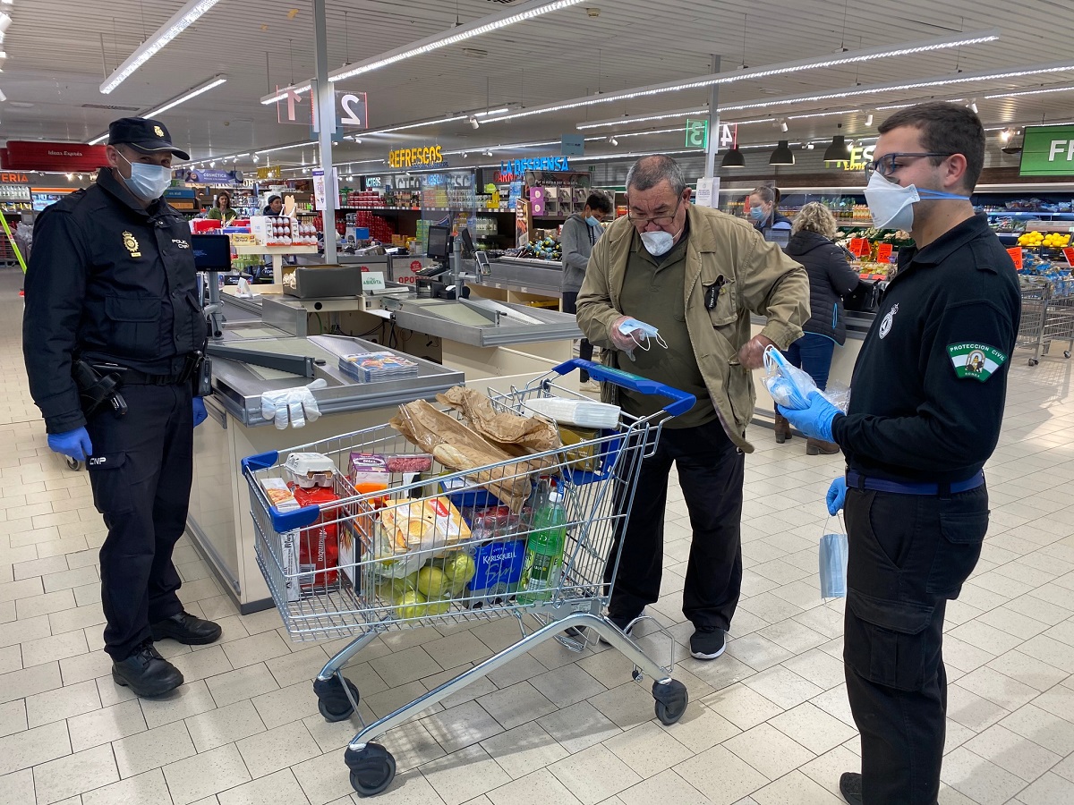 Policías nacionales y voluntarios de Protección Civil en el reparto de mascarillas de hoy.