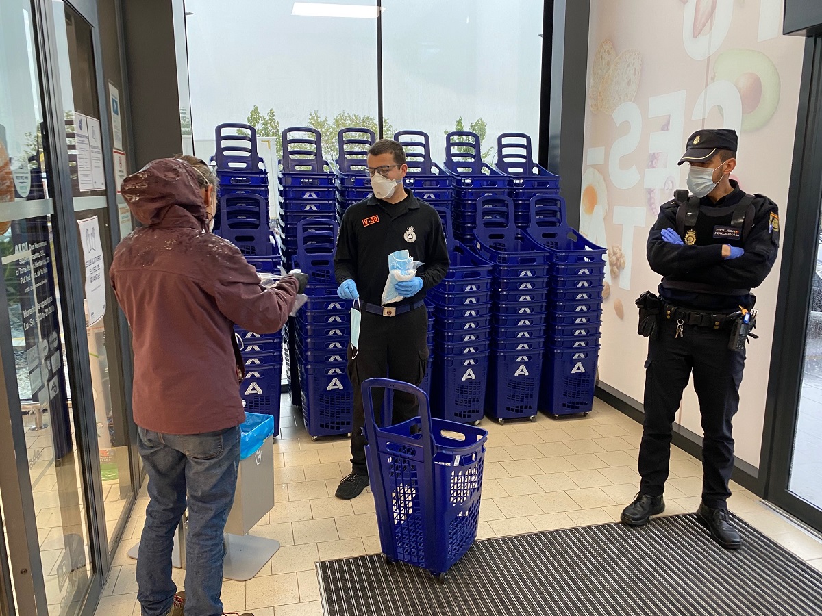 Un policía nacional y un voluntario de protección civil controlando el acceso a un supermercado.