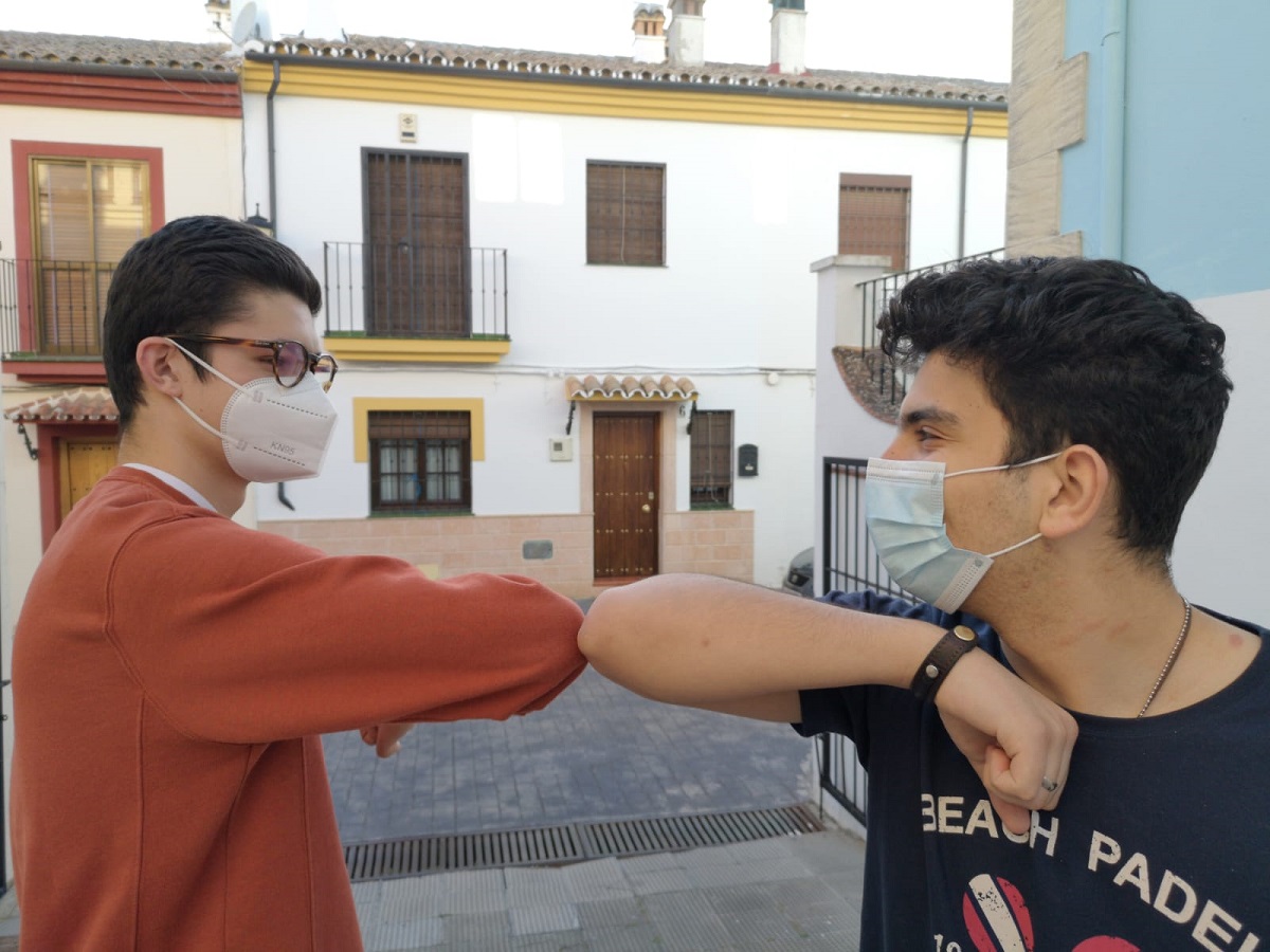 Dos jóvenes rondeños se saludan con los codos al encontrarse en la calle.