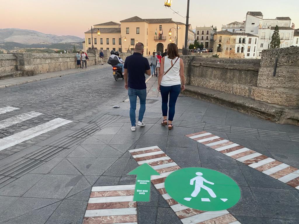Peatones paseando de forma organizada por las aceras en el Puente Nuevo de Ronda.