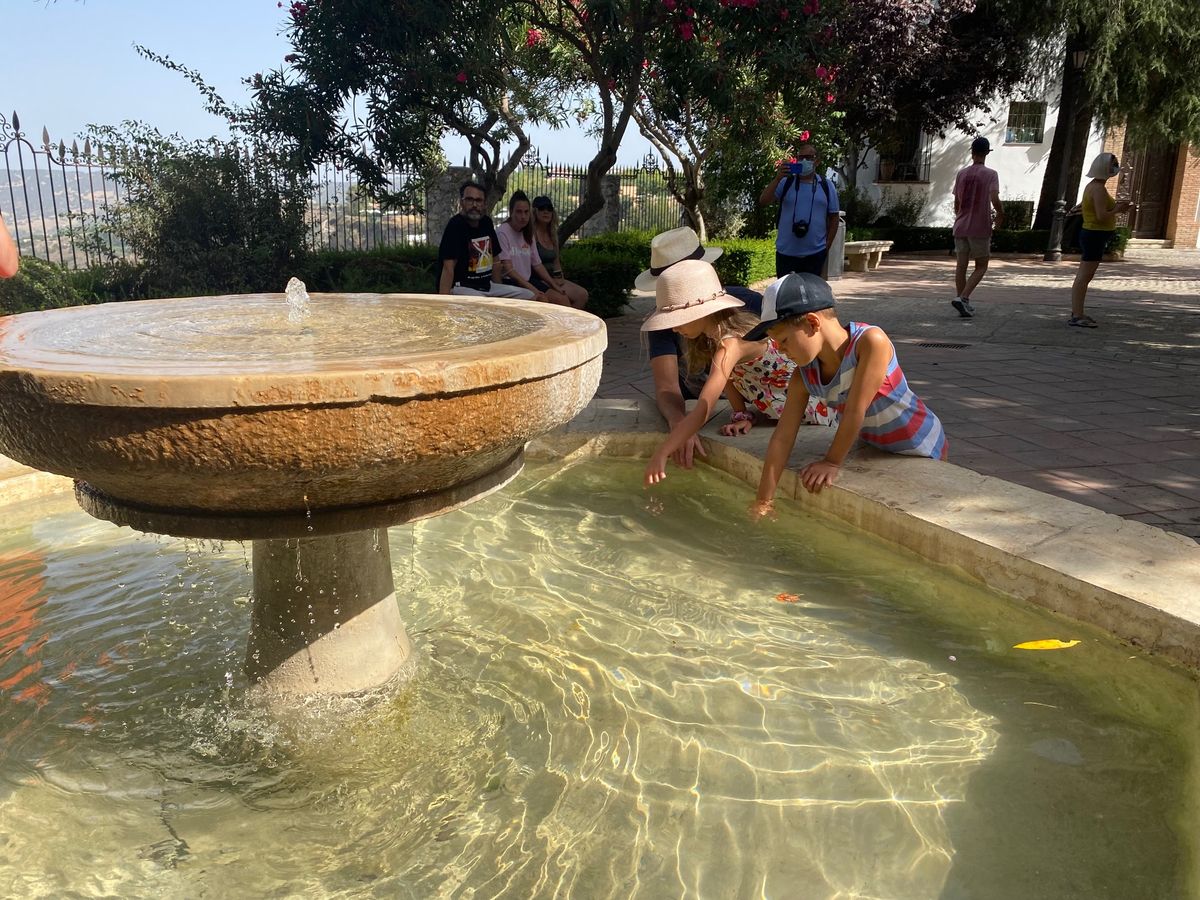 Dos niños juegan con el agua en la plaza del Campillo.
