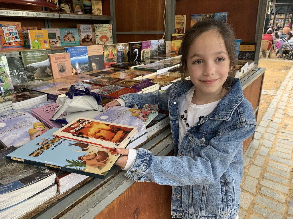 Una niña ojeando uno de los libros en la feria de este año.