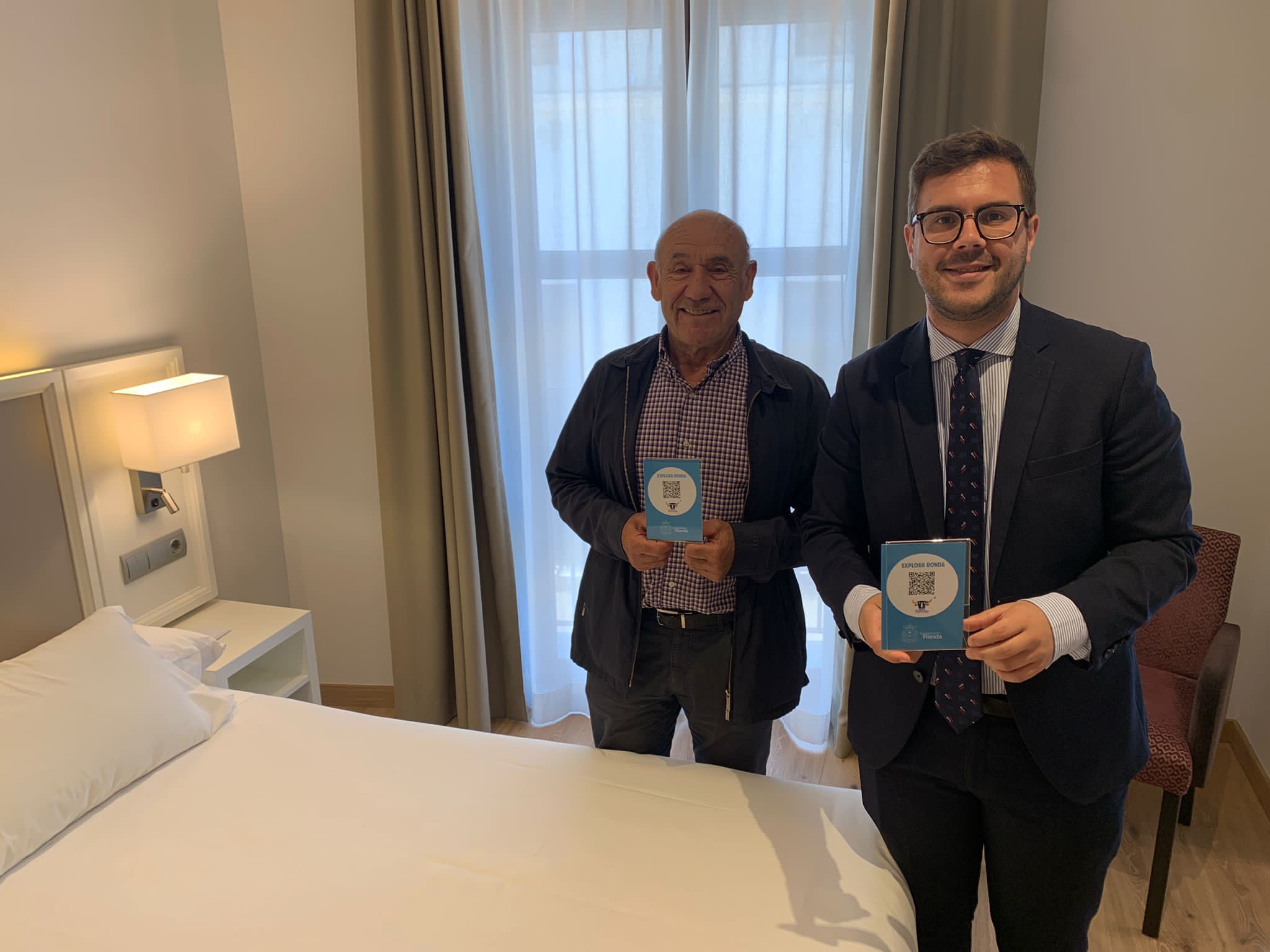 El concejal de turismo,con un hotelero de la ciudad muestra el código QR.