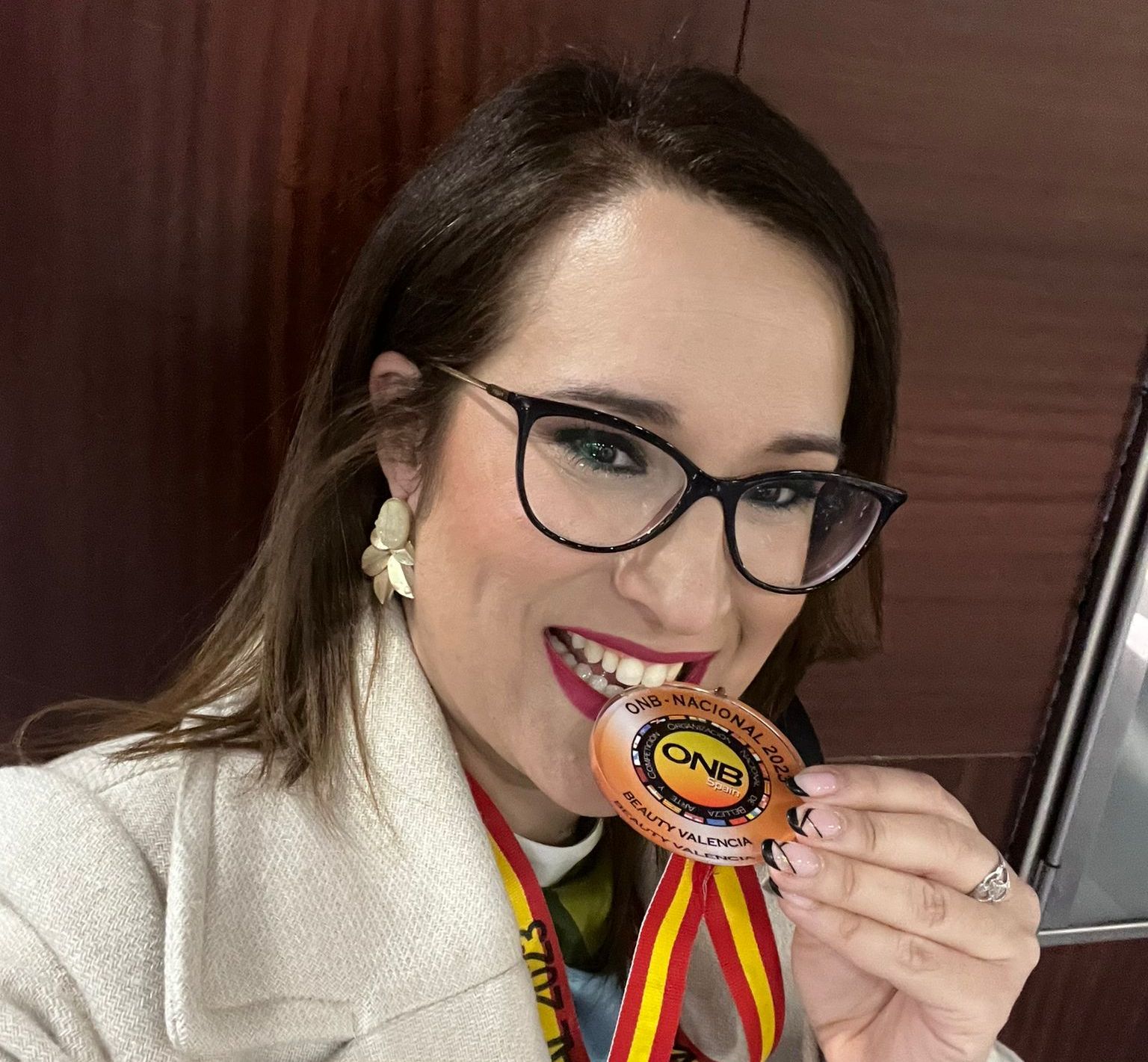 La joven peluquera muerde una de las medallas obtenidas en el campeonato nacional.