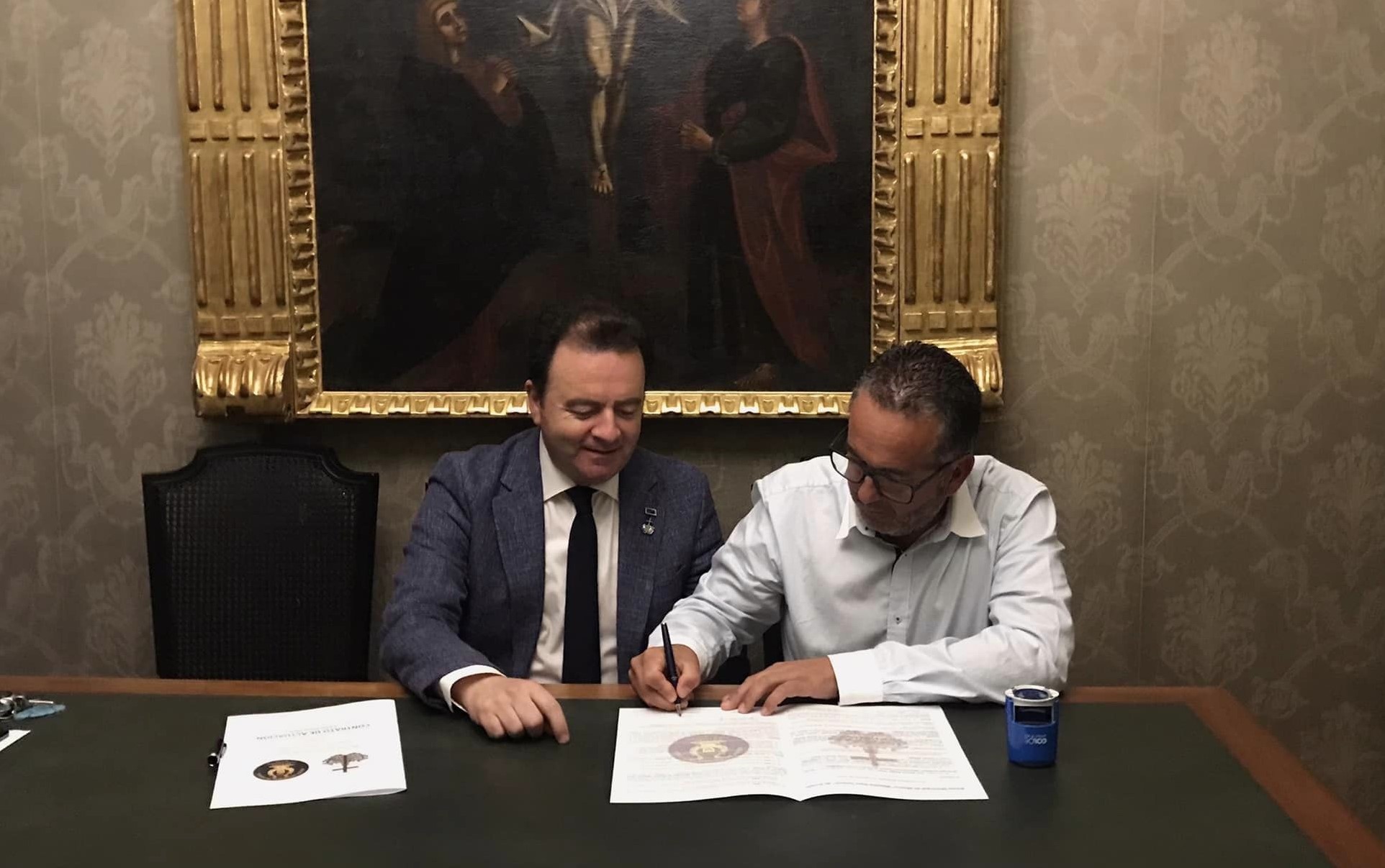 Momento en el que el hermano mayor y el director de la banda firman el convenio.