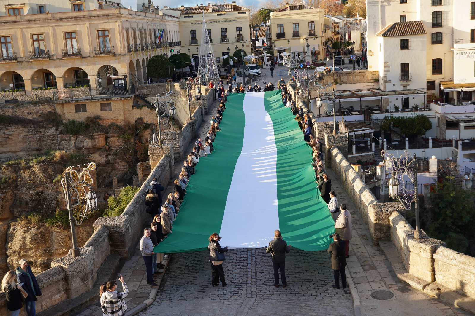 Miembros del PP de toda la provincia han desplegado una gran bandera de Andalucía en el Puente Nuevo.