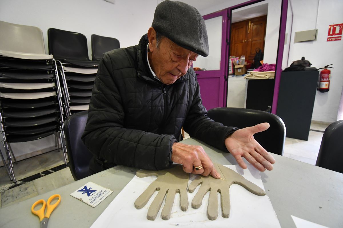 Uno de los vecinos moldea manos de cerámica para el mural.