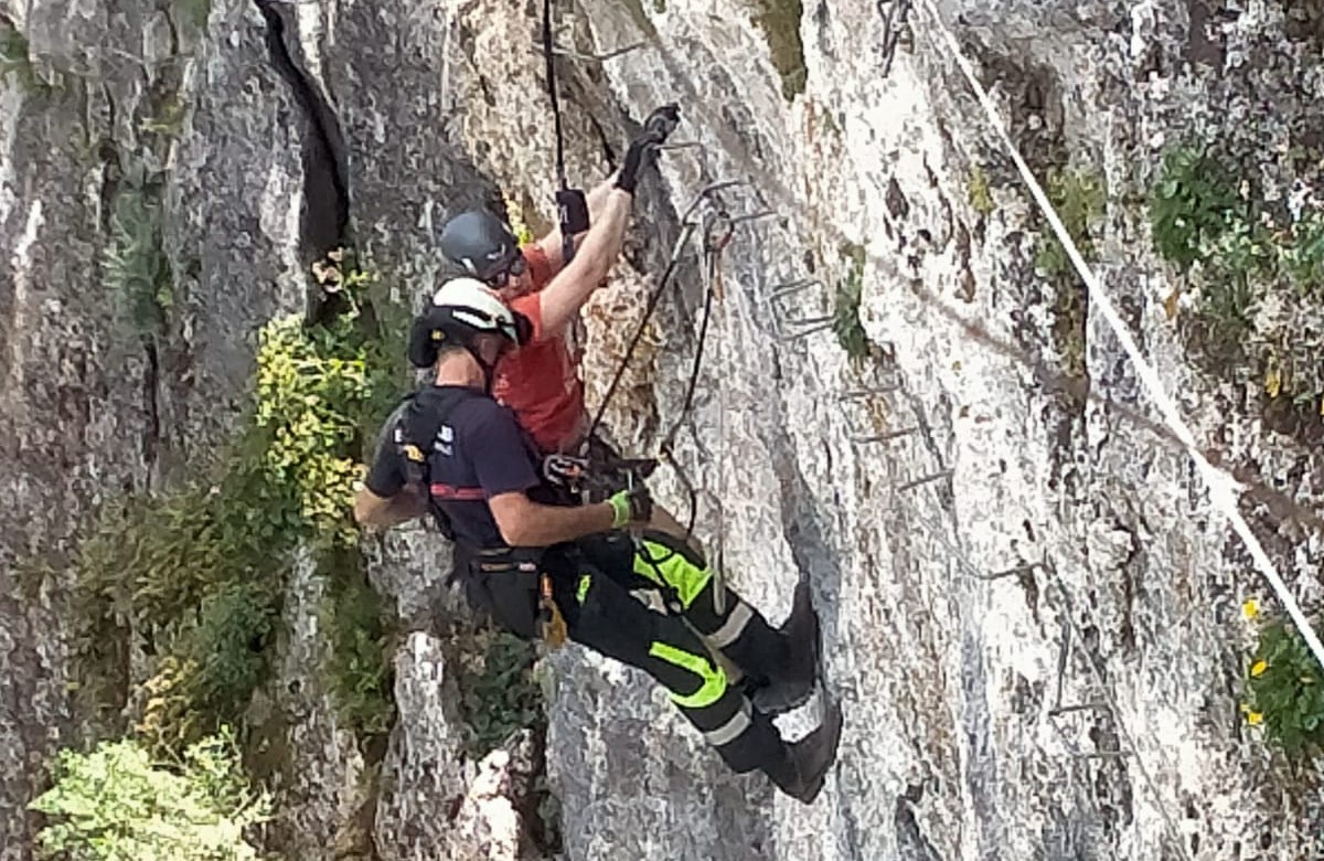Momento en el que uno de los bomberos logra llegar hasta el montañero.