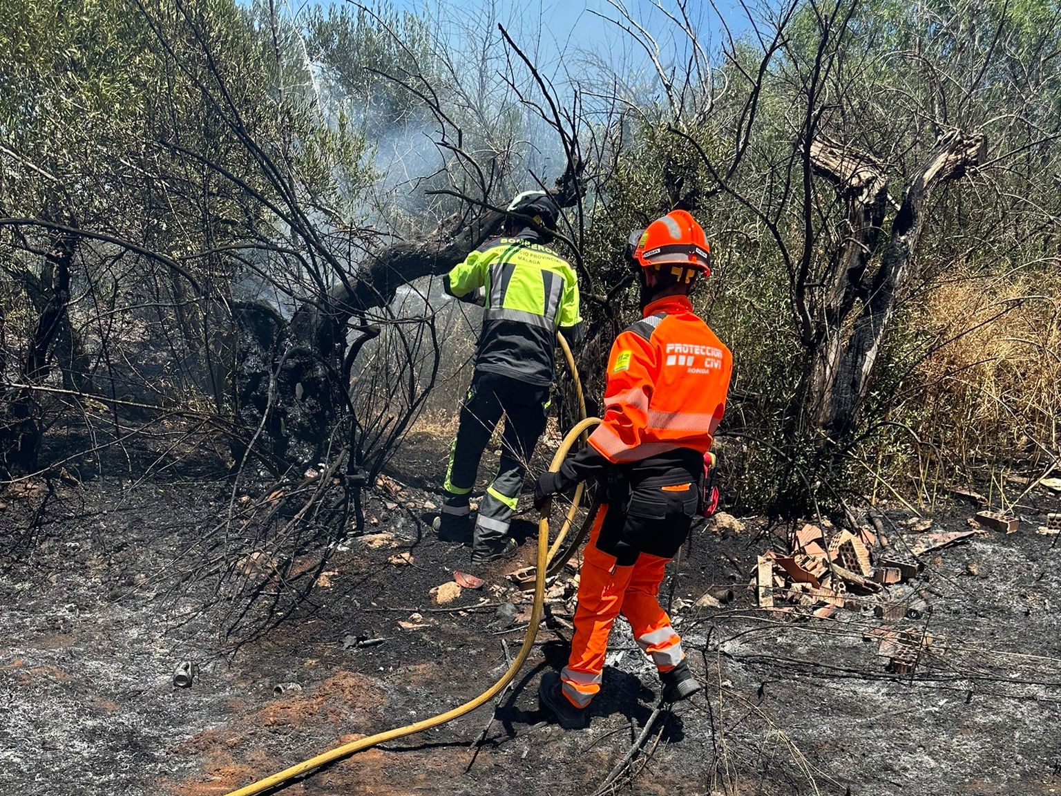 Un bombero y un voluntario de Protección Civil apagando el fuego en La Torrecilla.