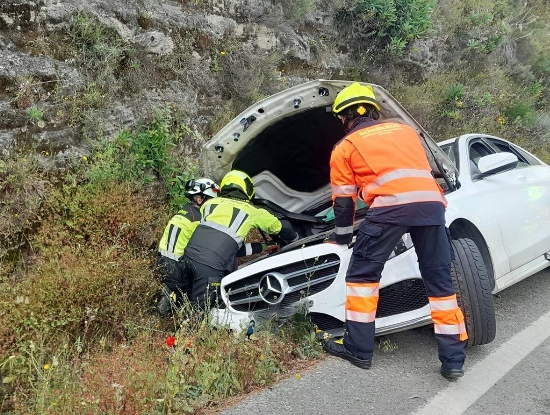 Miembros del Parque de Bomberos de Ronda junto al vehículo siniestrado.