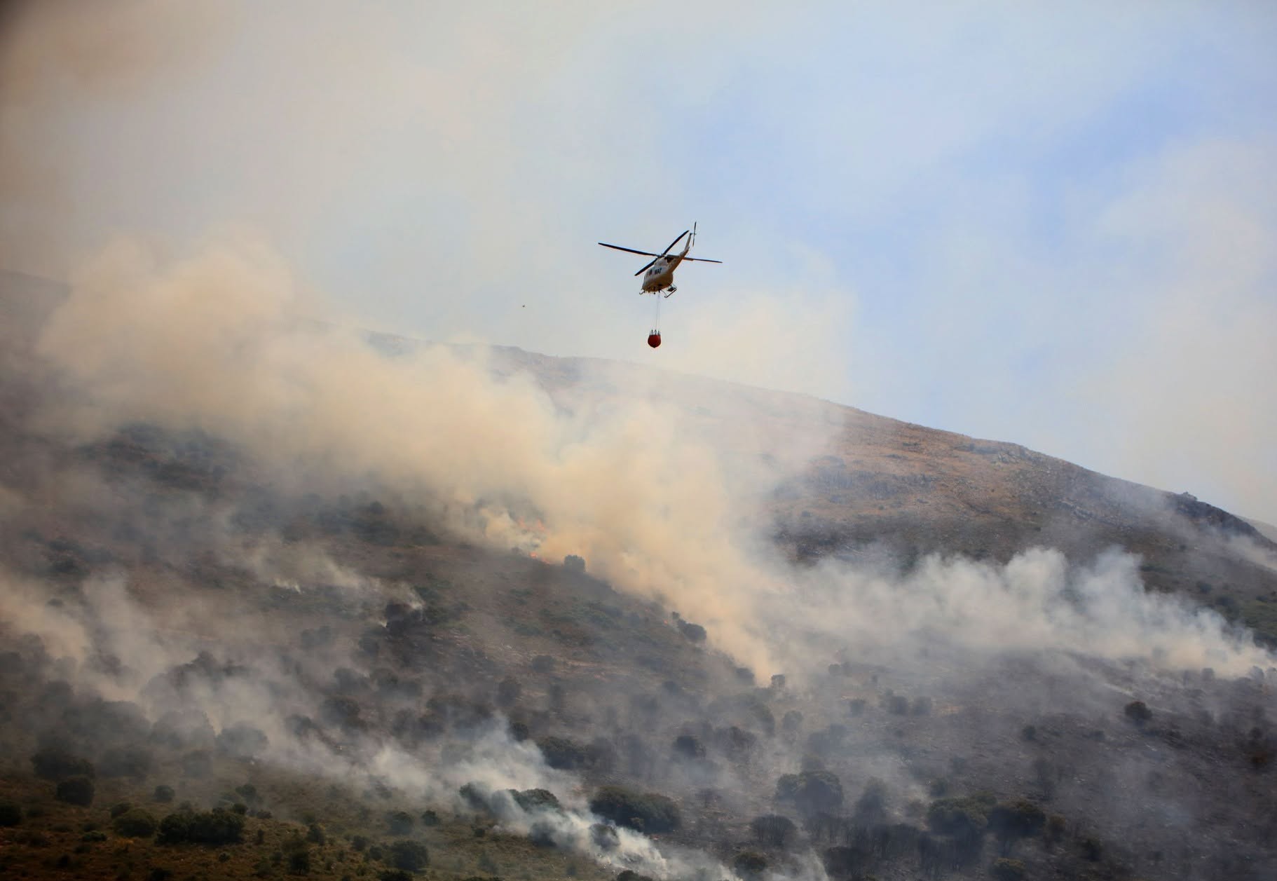Hasta cinco helicópteros han tenido que participar en las labores de extinción. Foto Karl Smallman.