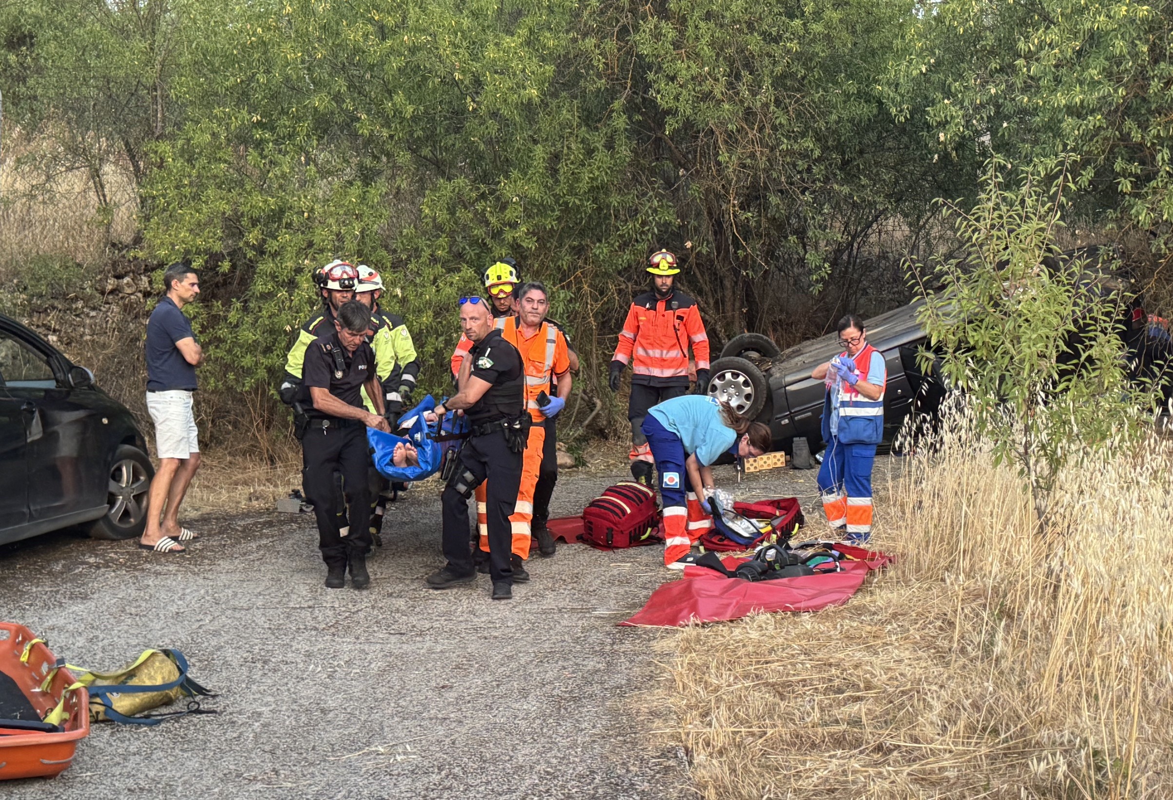 Momento en el que bomberos u policías locales trasladan en camilla a uno de los heridos.