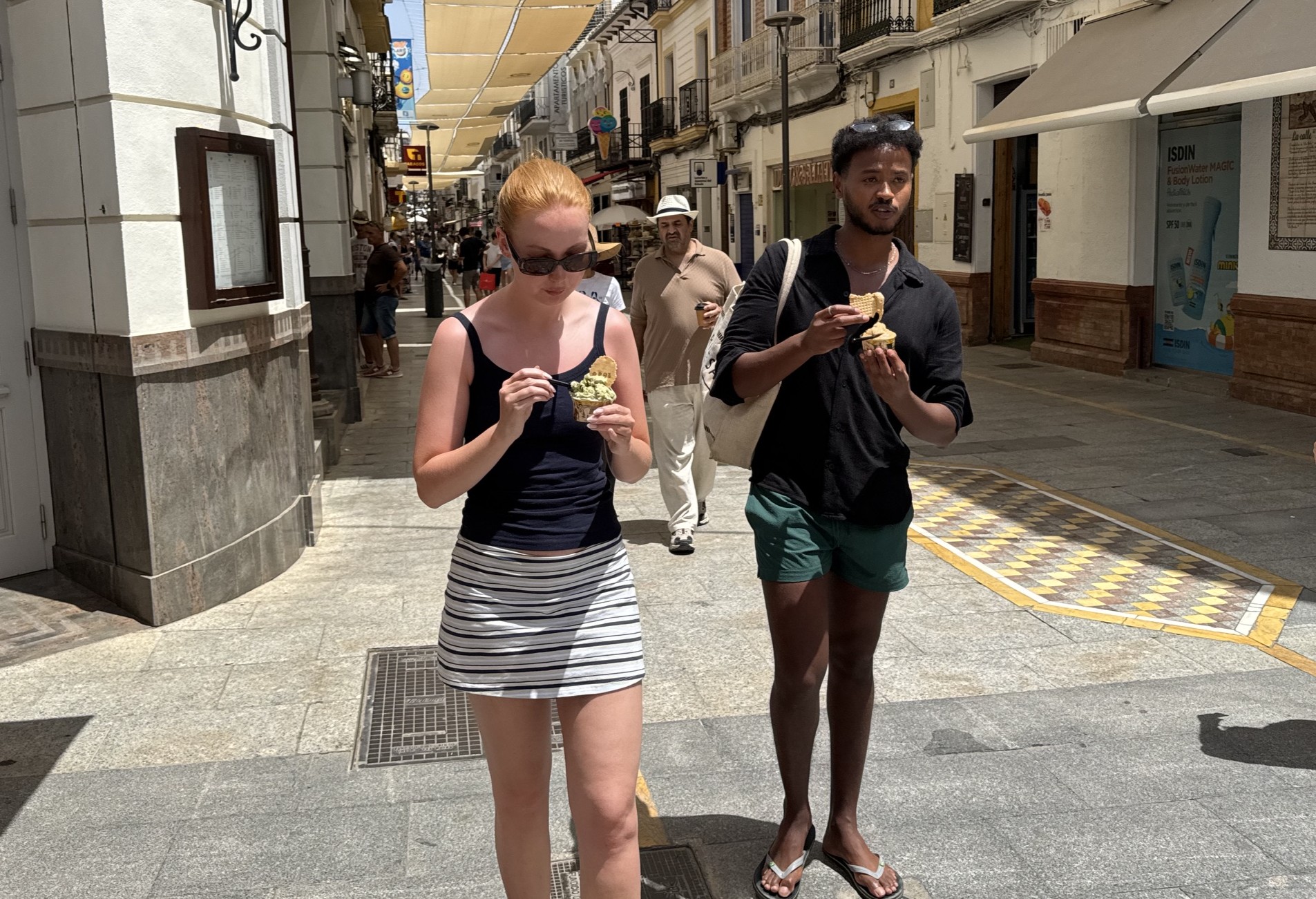 Dos turistas pasean por la calle de La Bola mientras se refrescan con un helado.