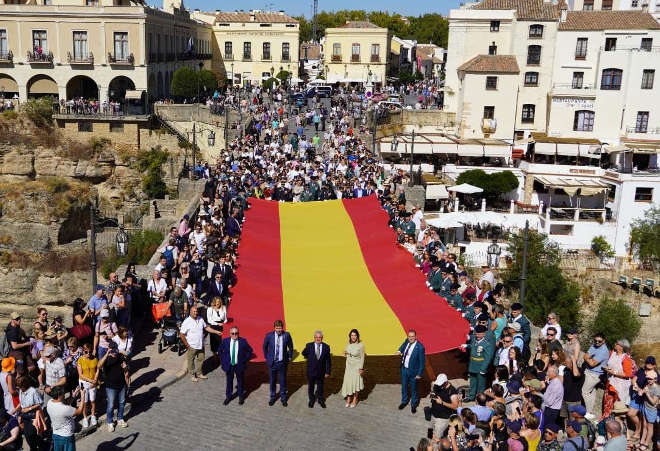 Momento en el que autoridades civiles y militares, y numerosos rondeños, despliegan la bandera de España en el Puente Nuevo.